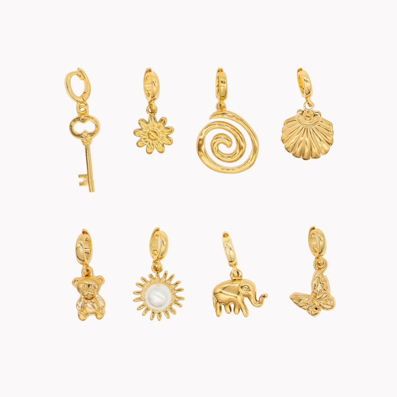 Set of gold charms including a key, sun, shell, bear, elephant, and butterfly on a white background.