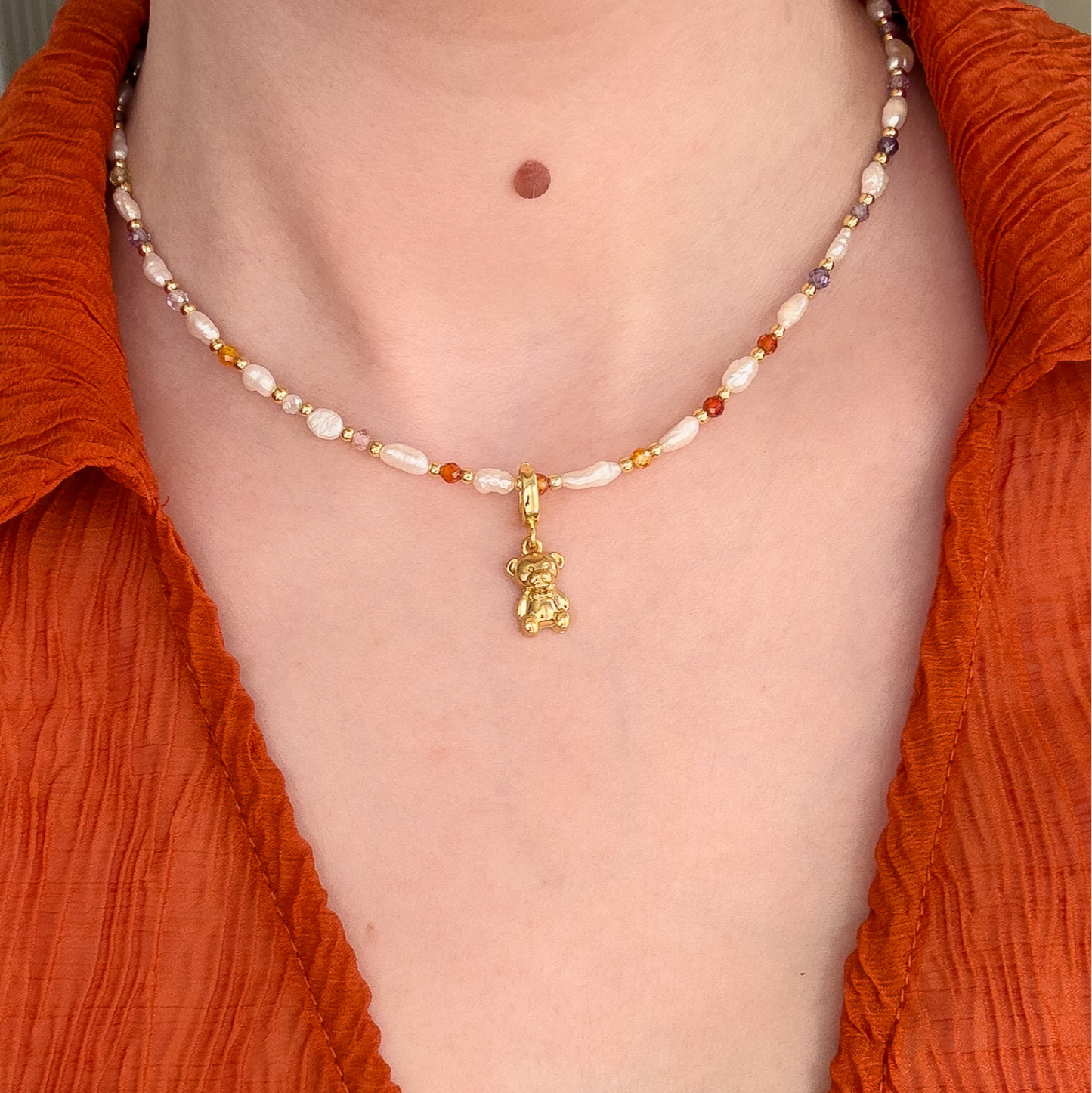 This image displays a charming necklace known as the "Teddy Charm". It features a delicate bead strand in shades of white freshwater pearls and gold pearls, interspersed with small, sparkling rhinestones.