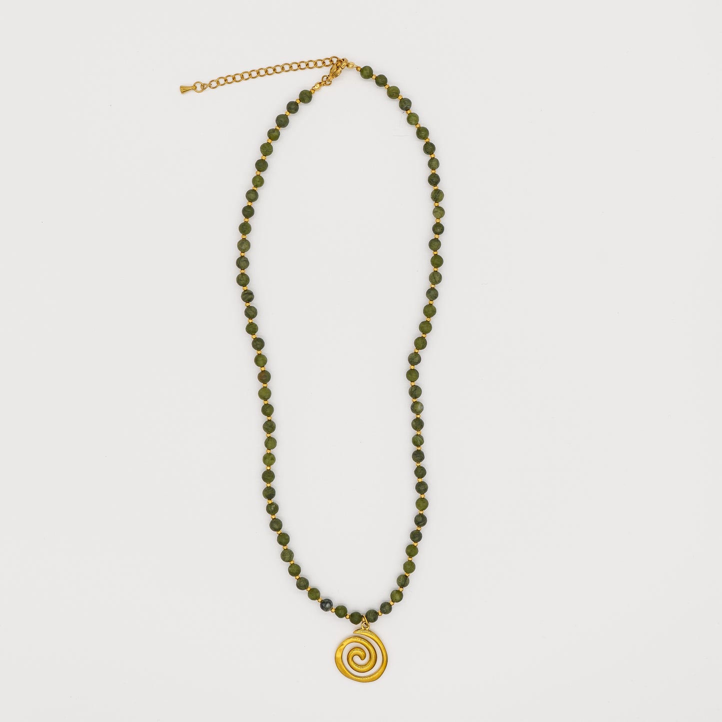 Necklace with green beads and gold spiral pendant on white background