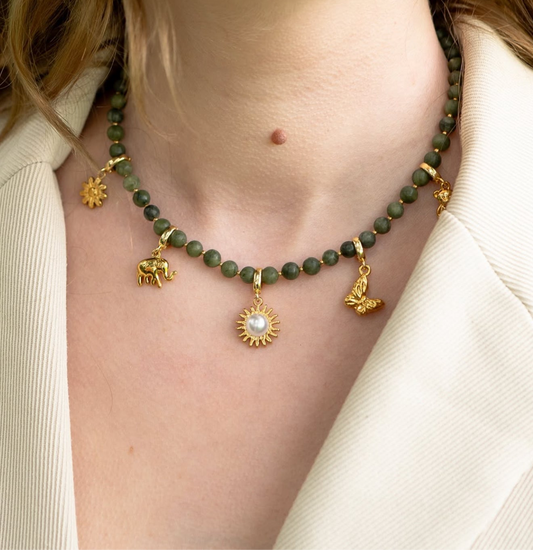 Necklace with green beads and gold charms worn by a person