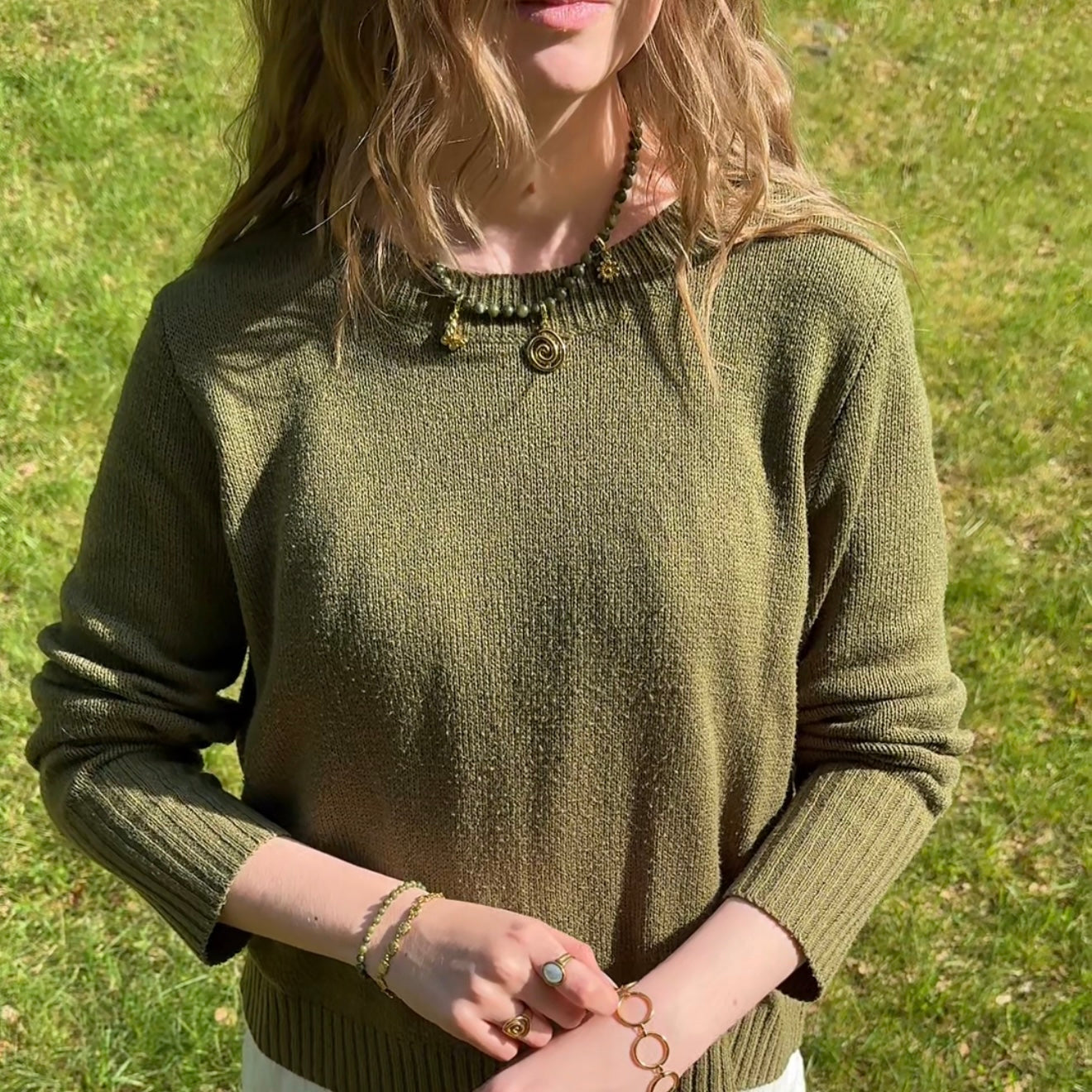 Person wearing a green sweater with a grassy background