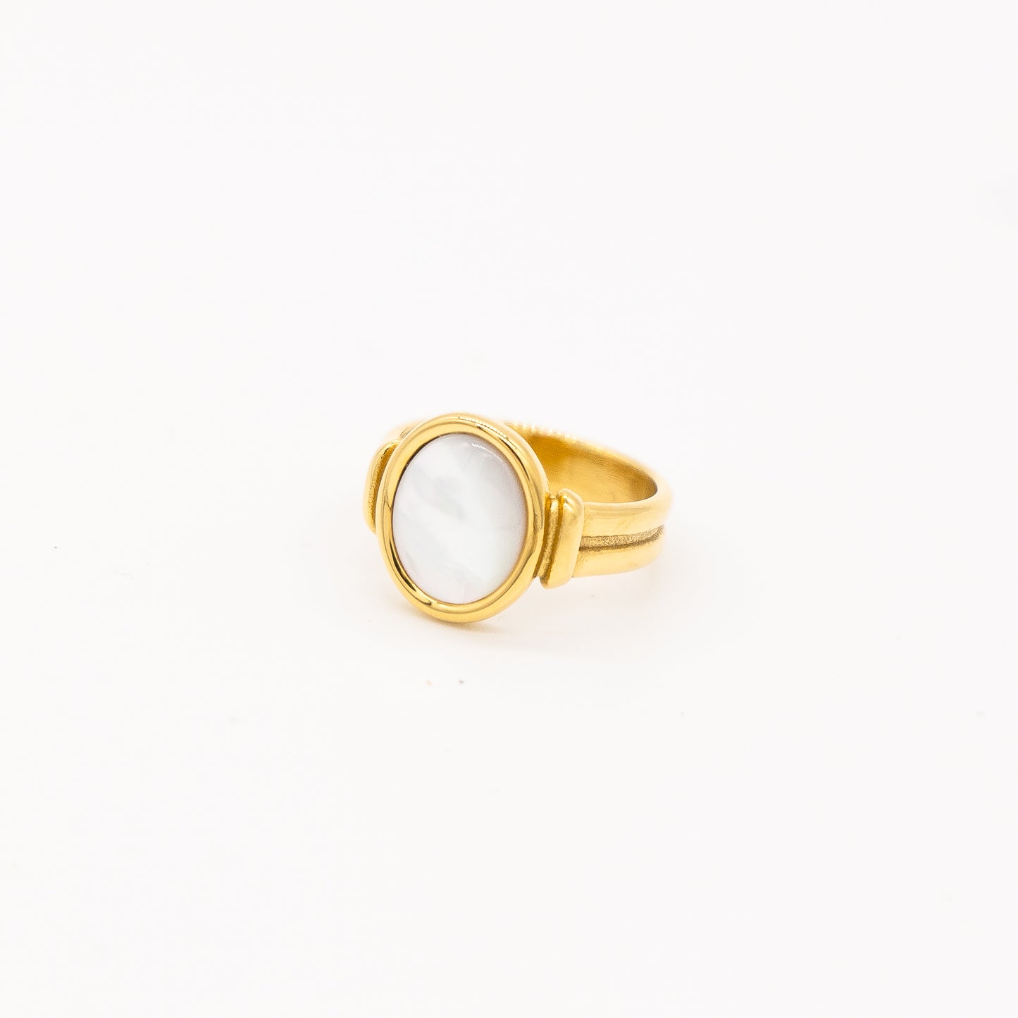 A gold-colored ring with a round natural pearl centerpiece, on a white background.