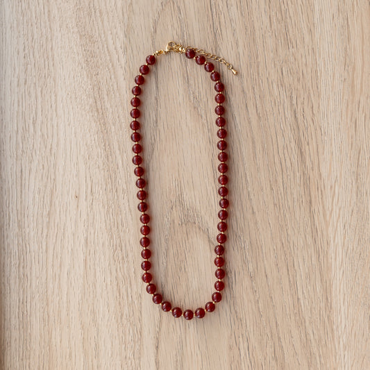 Red beaded necklace on a wooden surface