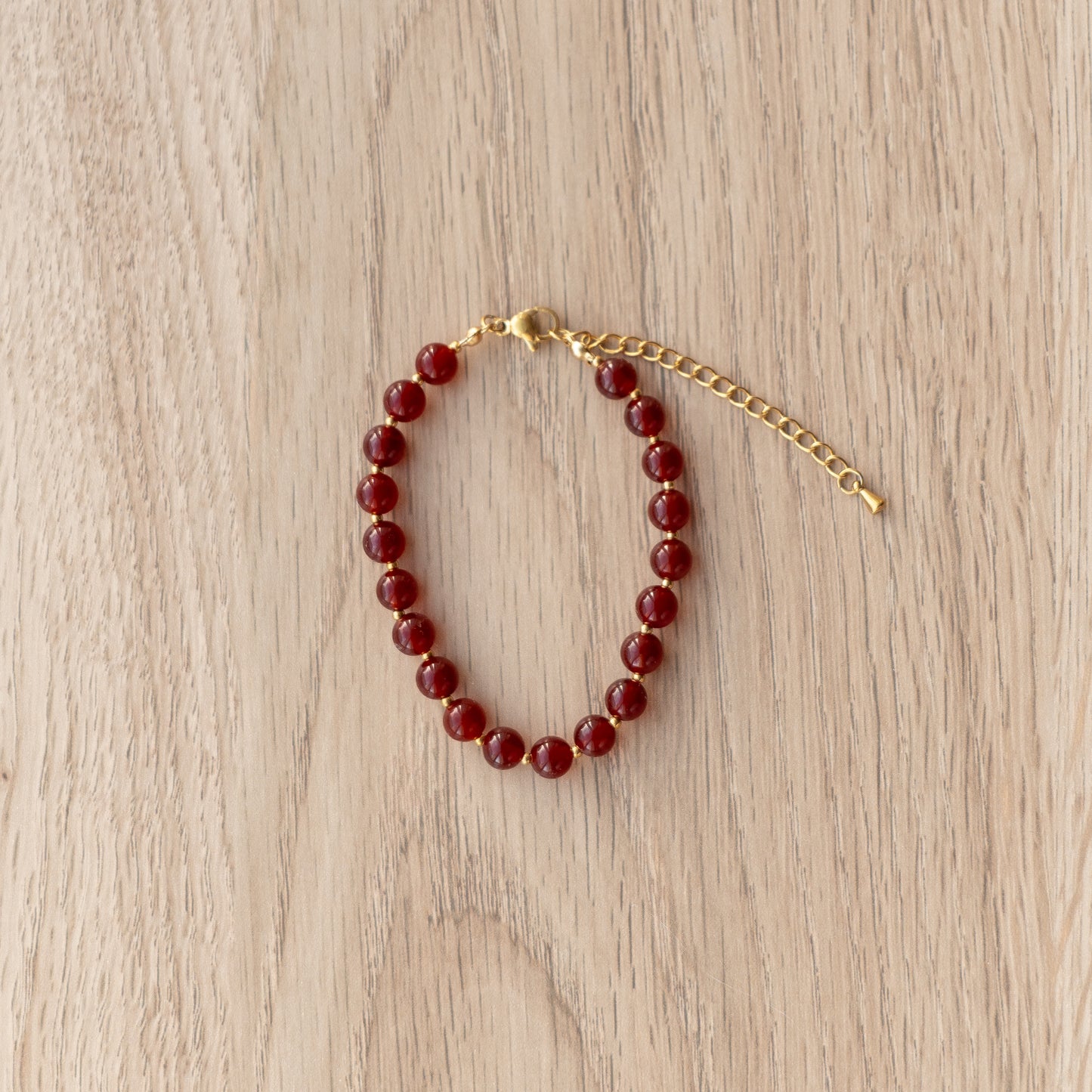 Beaded bracelet with gold clasp on a light wooden surface