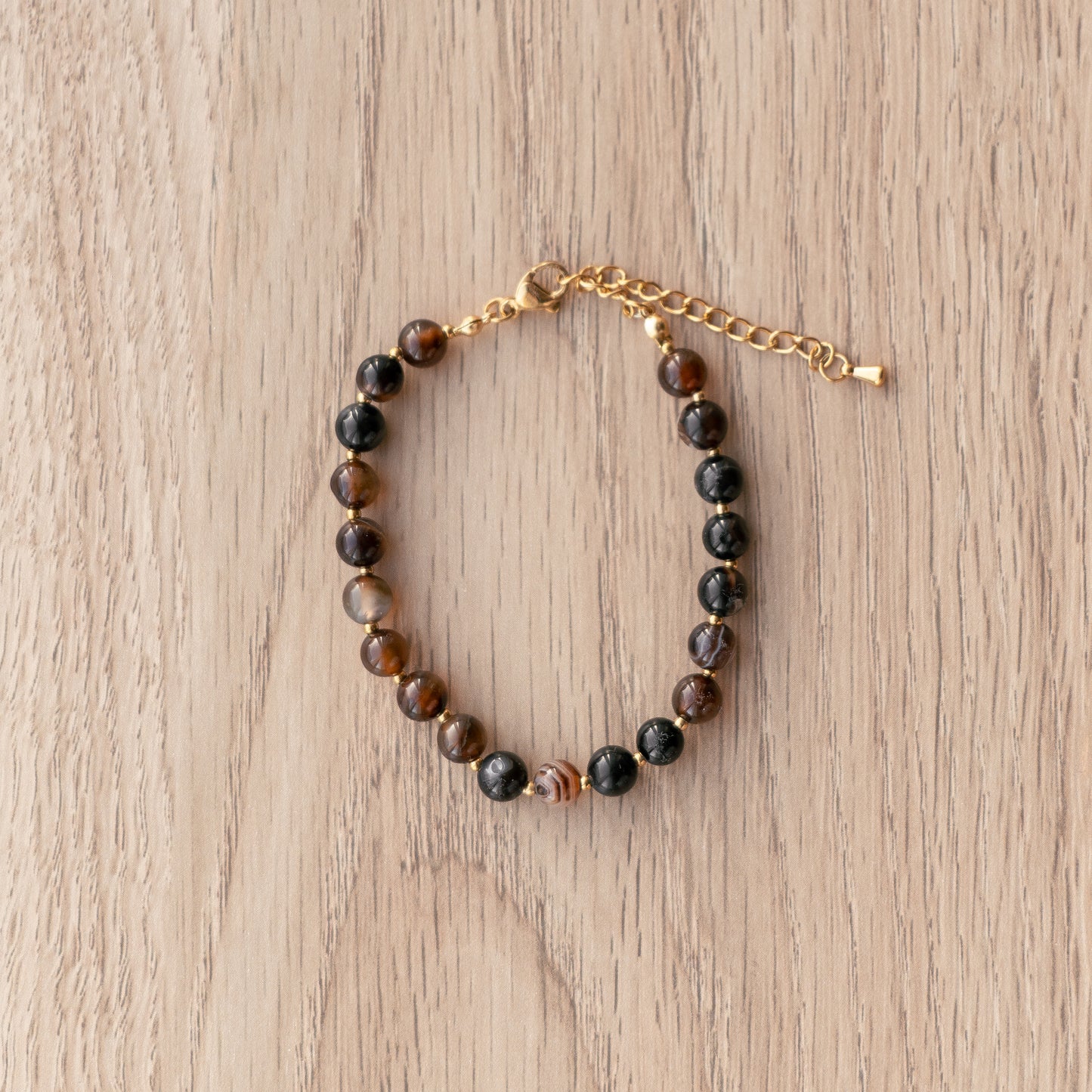 Beaded bracelet with gold chain on a wooden surface