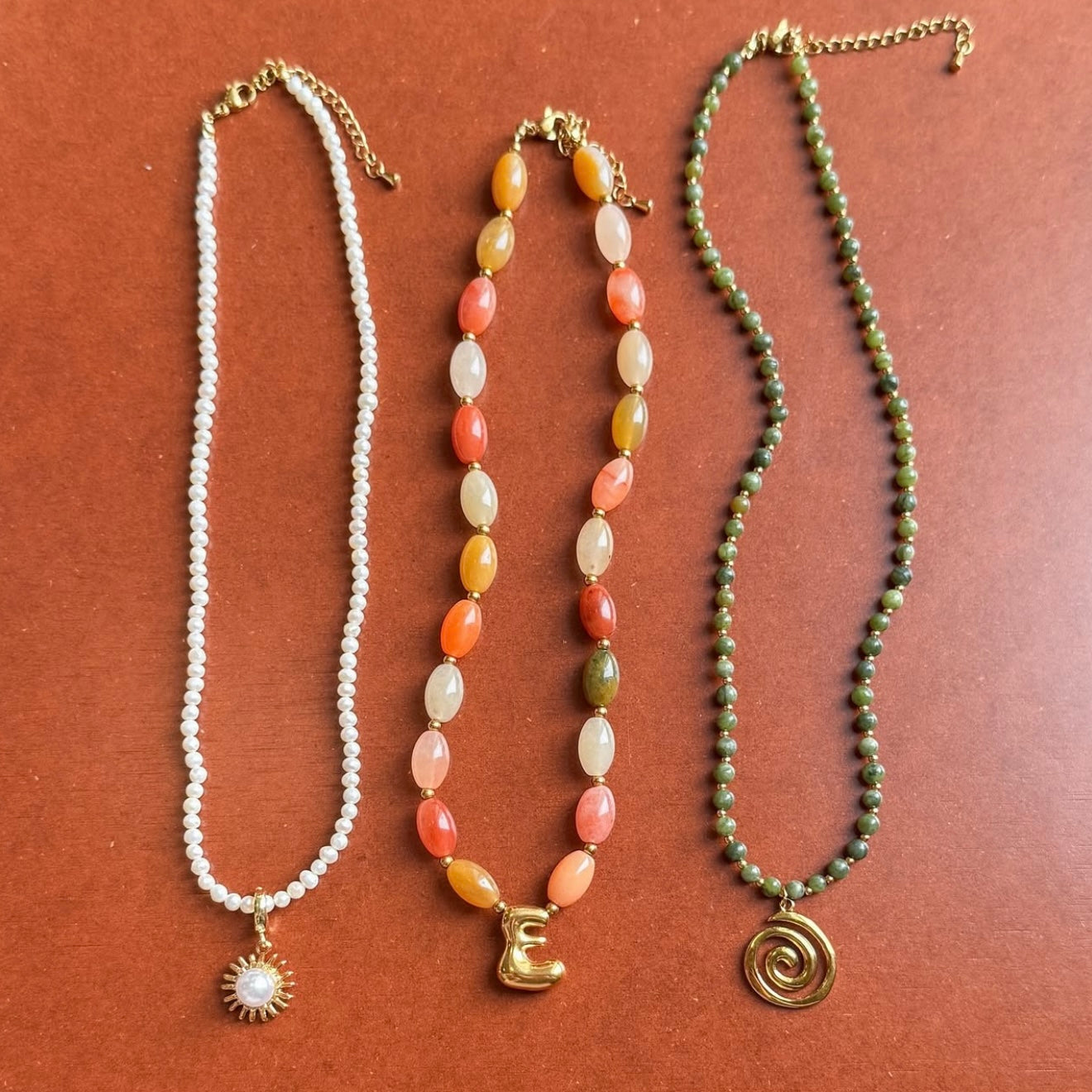 Three necklaces with different designs on a brown background