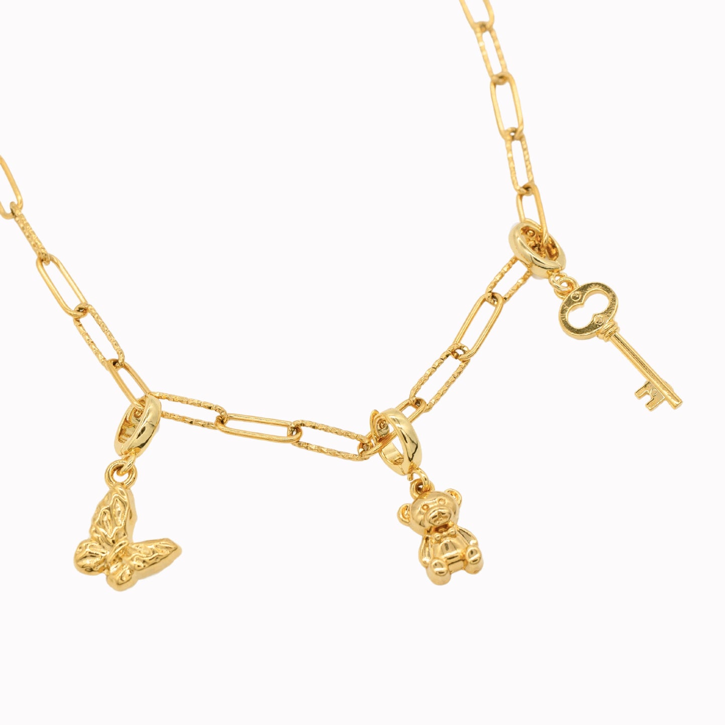 Gold necklace with butterfly, teddy bear, and key clip-on charms on a white background.