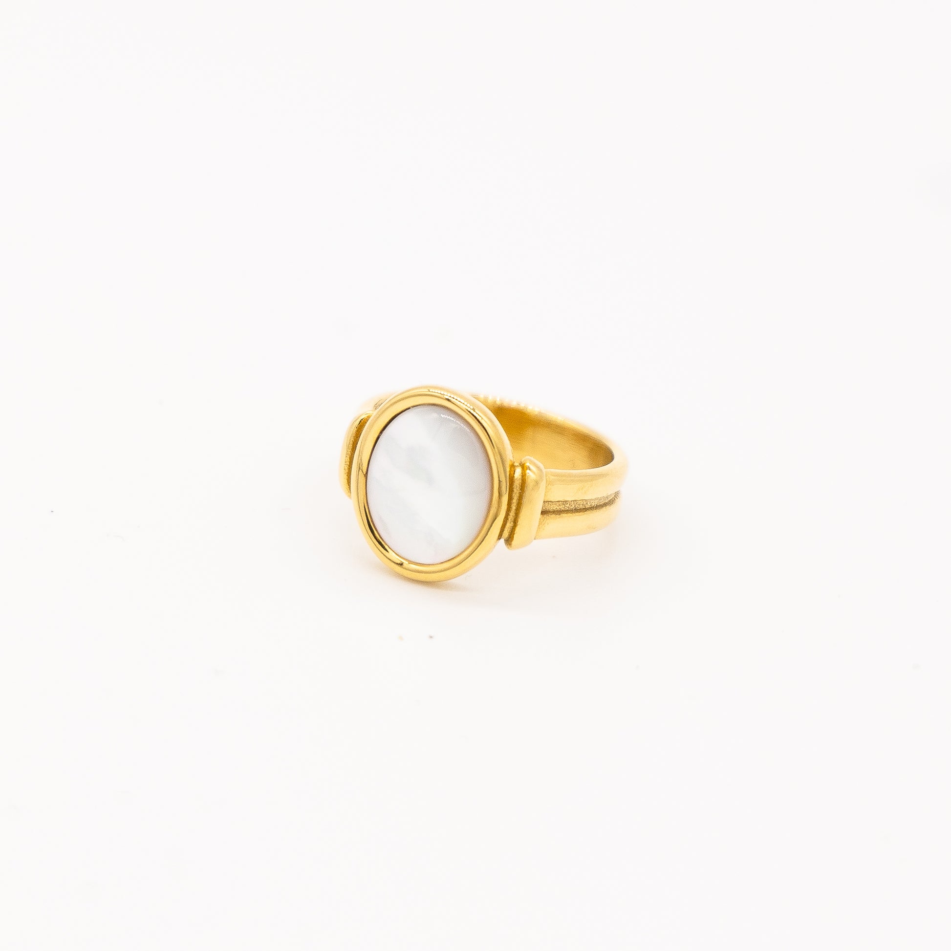 A gold-colored ring with a round natural pearl centerpiece, on a white background.