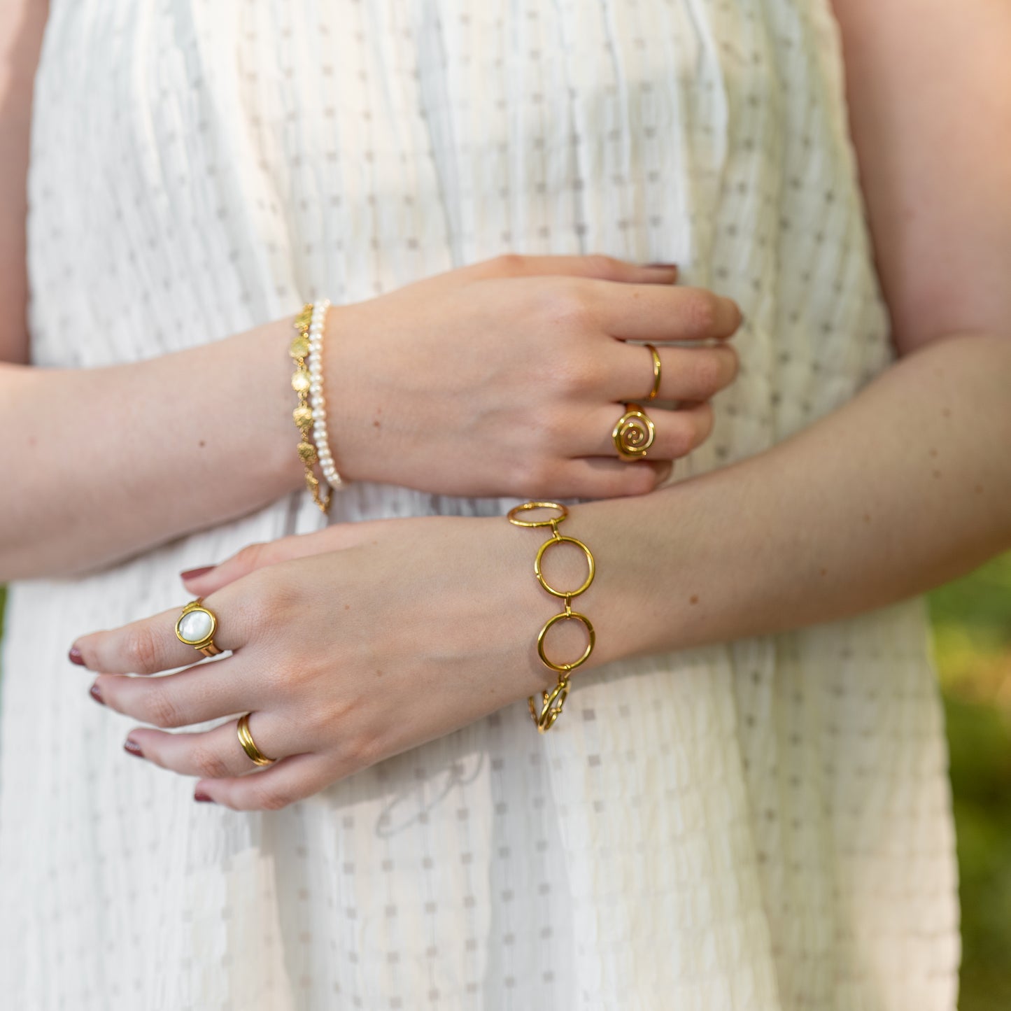 Close-up of a person's hands wearing gold jewelry with a blurred background