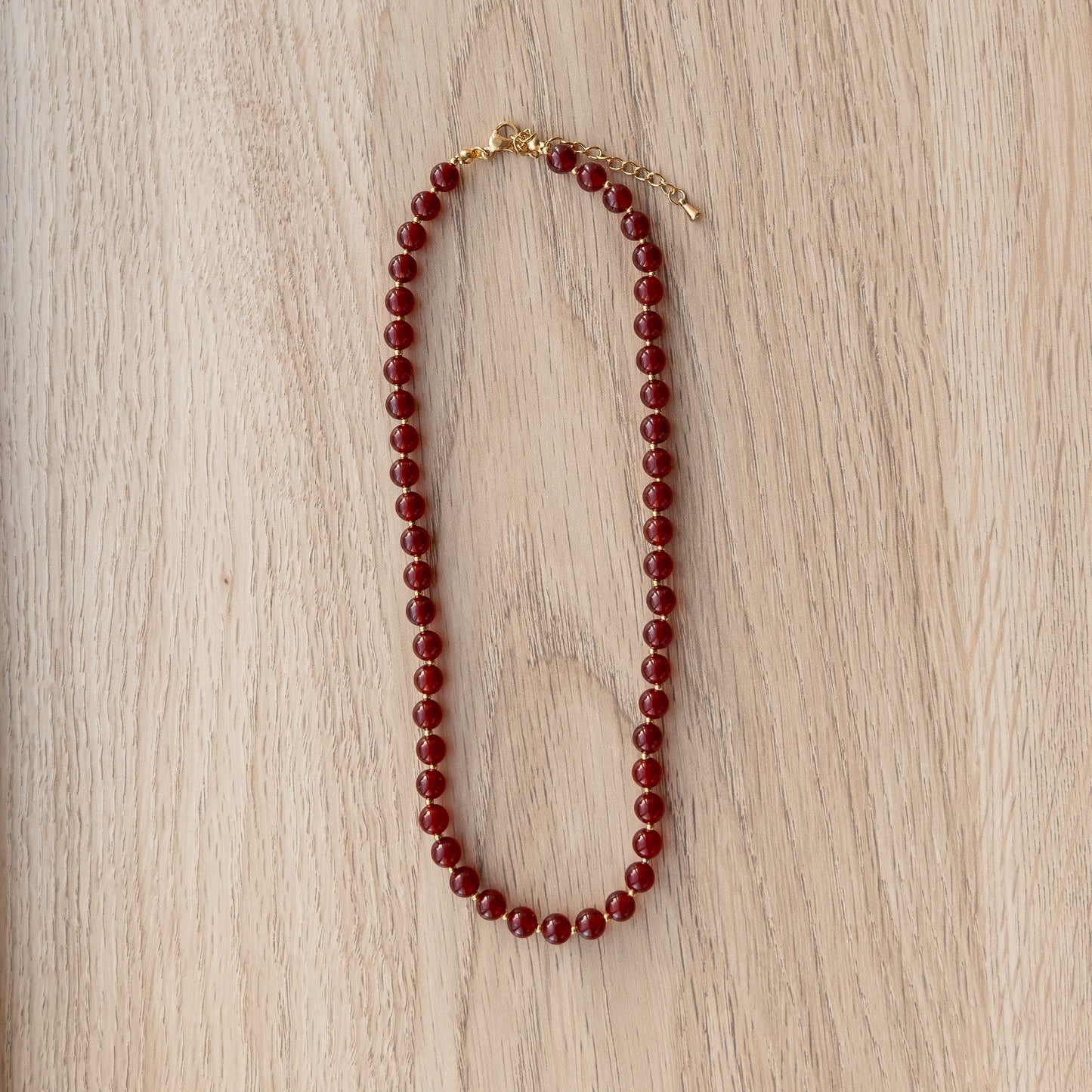 Red beaded necklace on a wooden surface