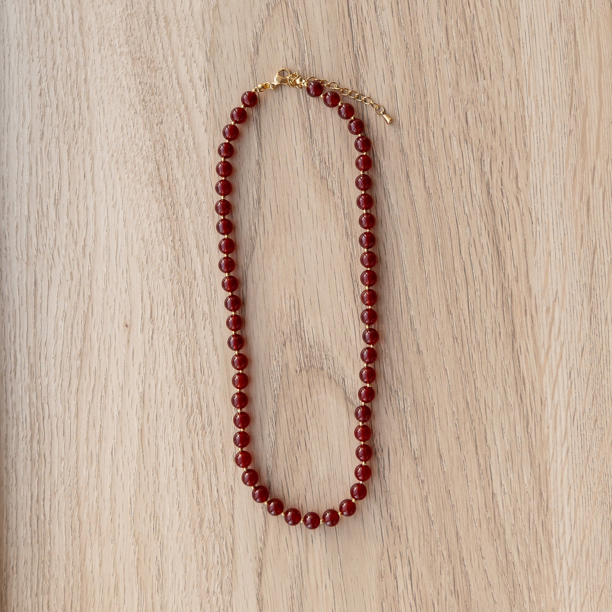 Red beaded necklace on a wooden surface