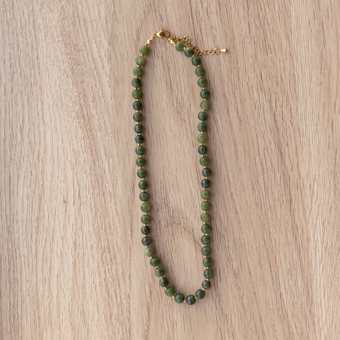 Green beaded necklace on a wooden surface