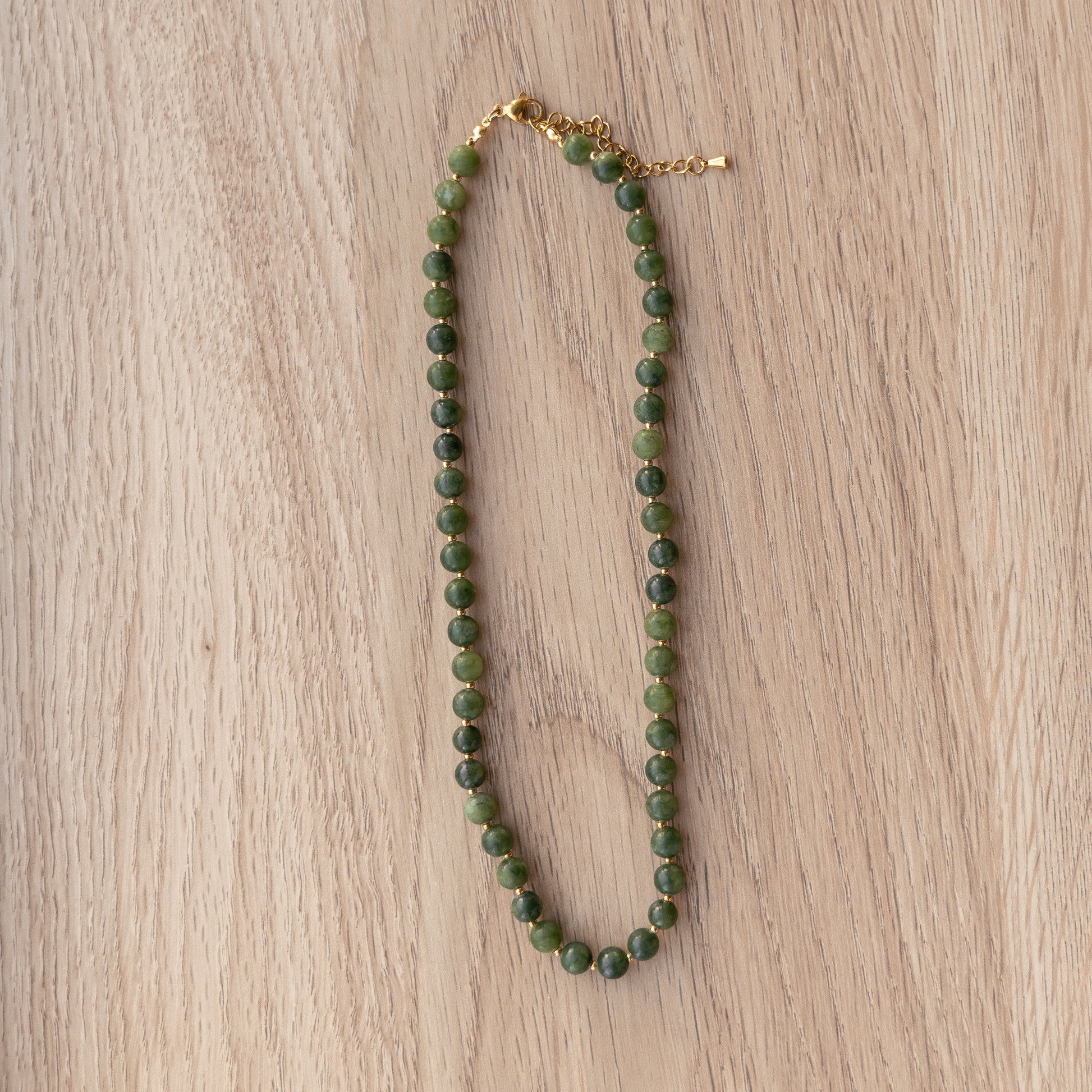 Green beaded necklace on a wooden surface