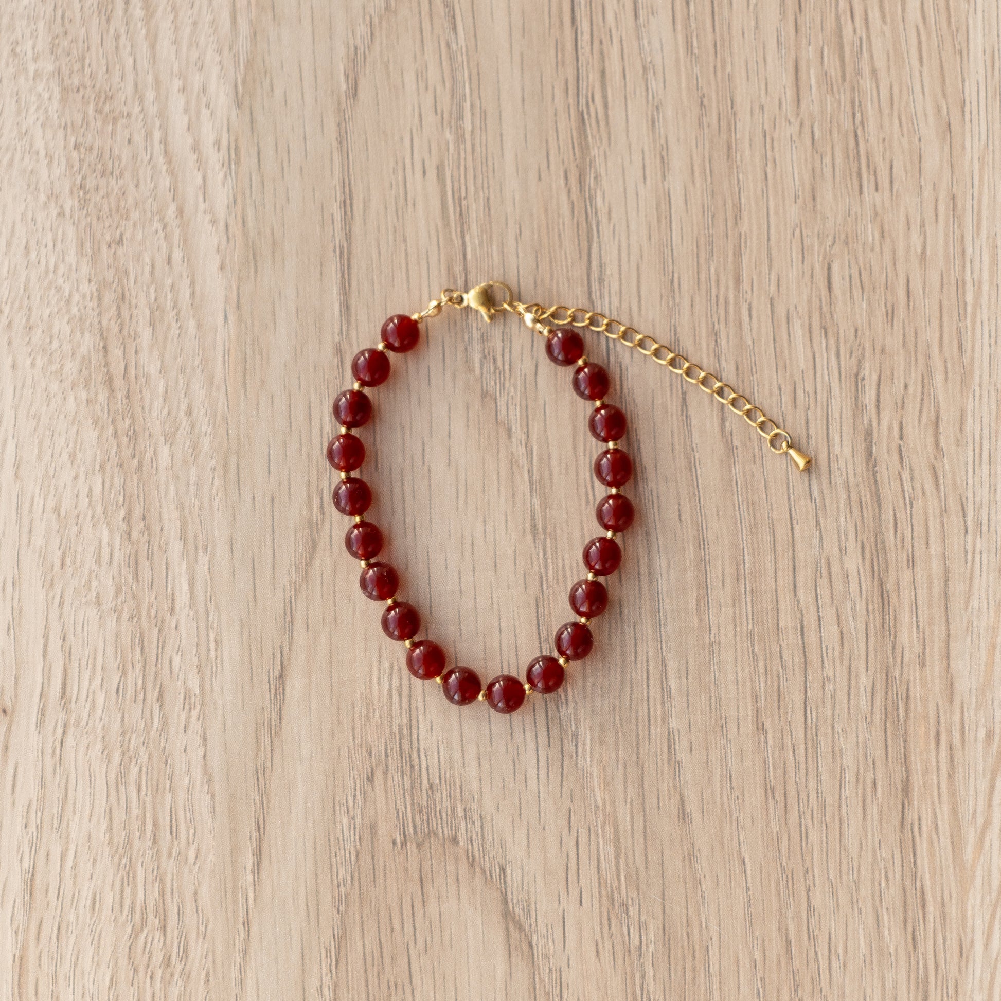 Beaded bracelet with gold clasp on a light wooden surface