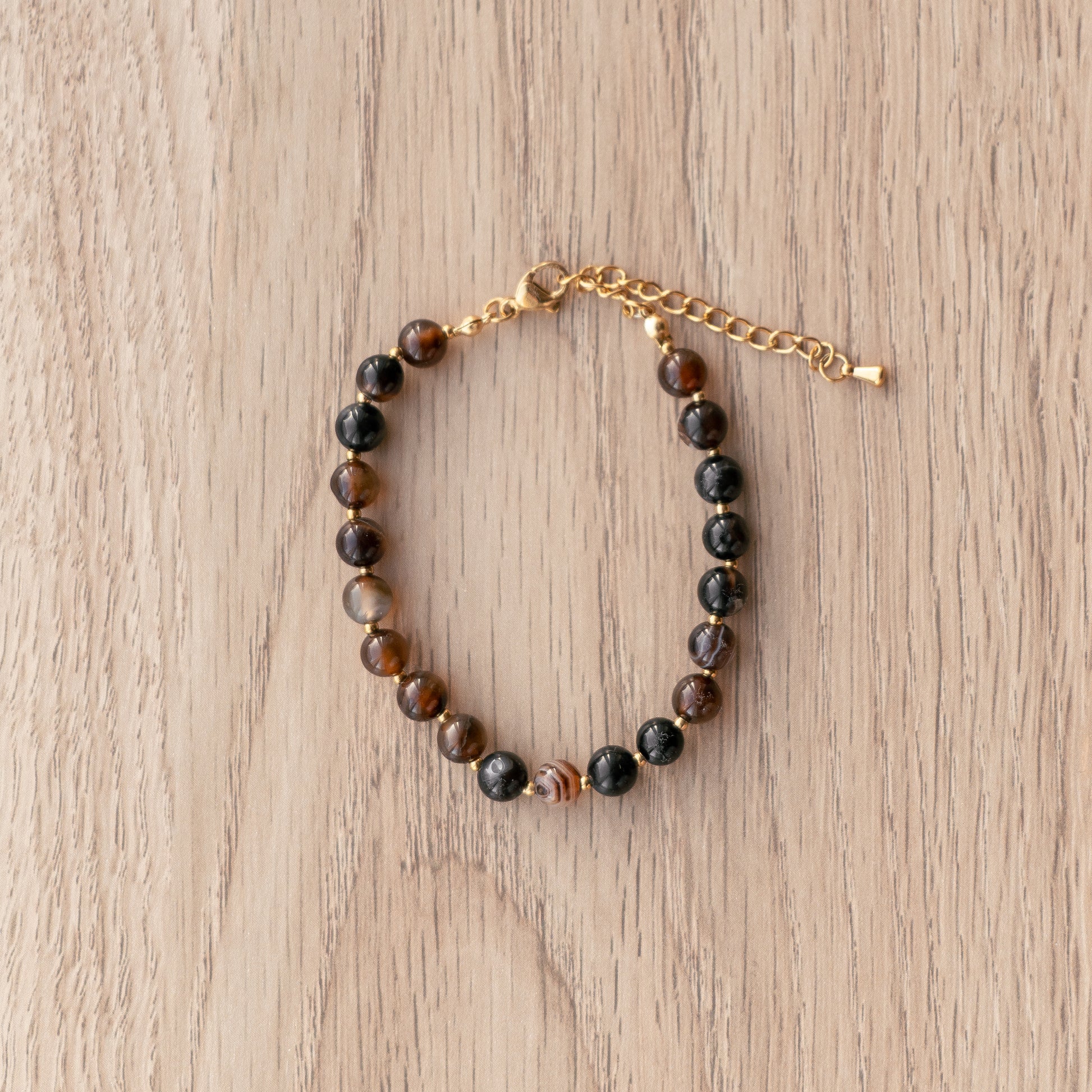Beaded bracelet with gold chain on a wooden surface